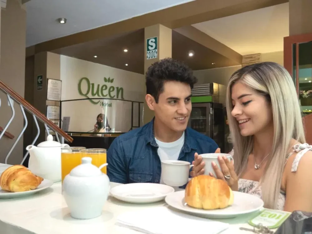 Pareja disfrutando de un croissant y zumo en la cafetería Hotel Queen Lima Pareja disfrutando de un croissant y zumo en la cafetería Hotel Queen Lima